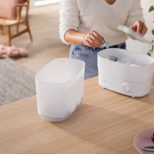 Madre usando el esterilizador Philips Avent para desinfectar biberones de bebé