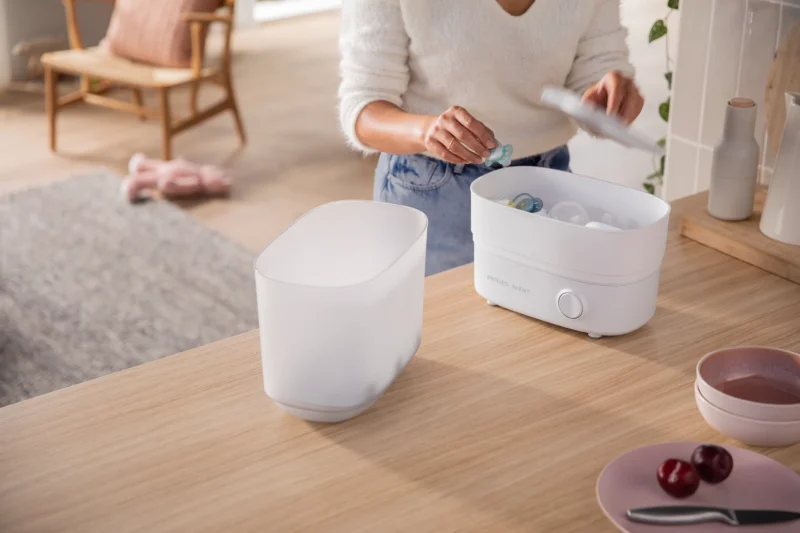 Madre usando el esterilizador Philips Avent para desinfectar biberones de bebé